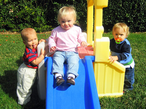 3 babies playing on small slide