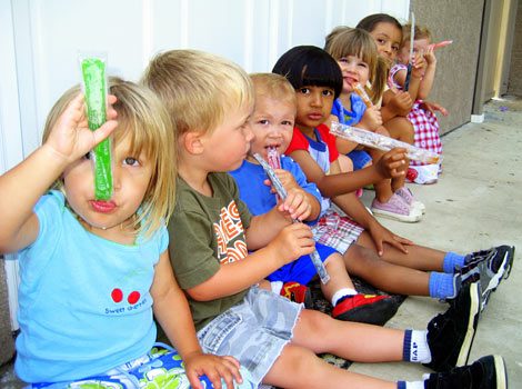 7 children sitting eating their popsicles