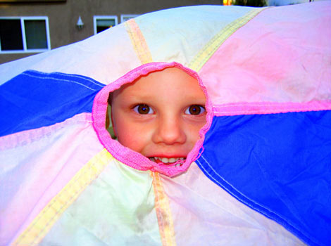 child looking out through play parachute